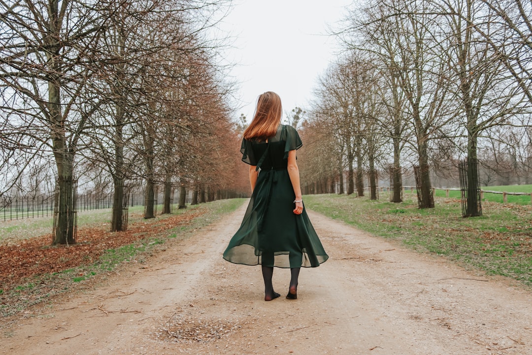 woman-wearing-green-dress-walking-on-sand-pathway-jjgkrrh-jji